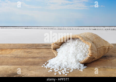 Meersalz in Tasche. Kristalle des Salzes im Sack auf Tisch mit salzigen See im Hintergrund. Beutel mit Meersalz hergestellt auf Bauernhof Stockfoto