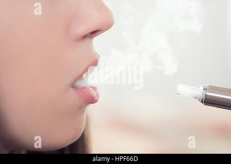 Frau rauchen elektronische Zigarette und Rauch zu genießen. Nahaufnahme Detail weiblich mit elektronischen Zigarette, horizontale erschossen. Mädchen raucht Stockfoto