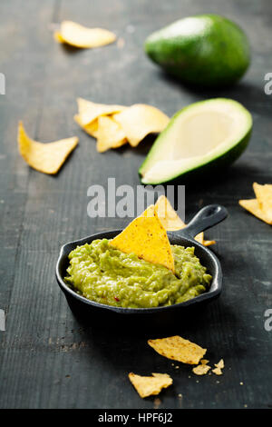 Mexikanische Nachos Chips mit hausgemachten frischen Guacomole Soße über alte Hintergrund. Mit Platz für text Stockfoto