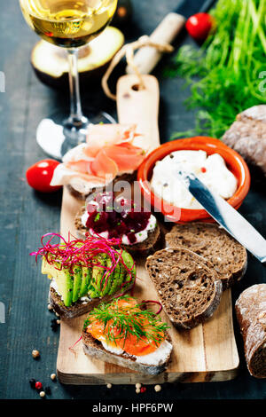 Leckere Schwarzbrot sandwiches, Withsalmon, Avocado, rote Beete, Frischkäse, Schinken, Kräuter und Gewürze Stockfoto