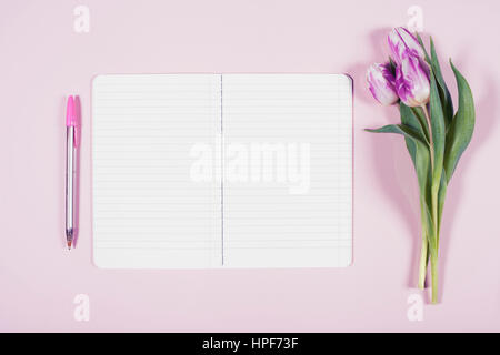 Rosa Tulpen und Notebook auf rosa Hintergrund. Flach zu legen. Draufsicht. Stockfoto