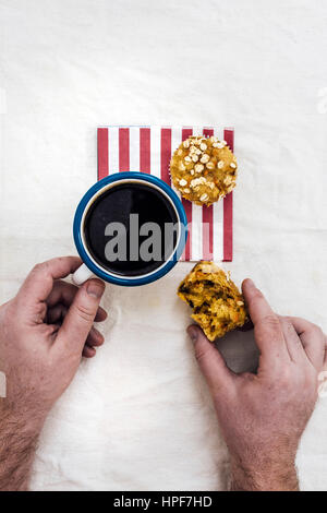 Ein Mann mit Karotten-Muffins mit Kaffee auf eine rot gestreifte Serviette aus Draufsicht fotografiert. Stockfoto