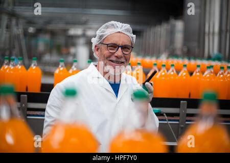 Porträt des Lächelns Fabrik Ingenieur Stand in der Nähe Produktionslinie mit Walkie-Talkie in Flasche Fabrik Stockfoto