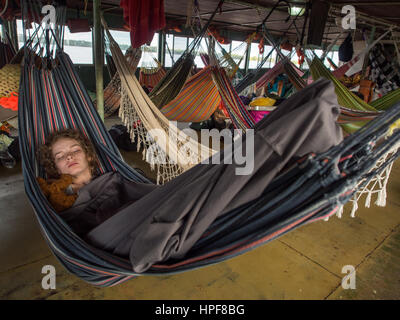 Amazonas, Peru - 13. Mai 2016: Junge Frau ruht sich auf Hängematten auf einem Deck des Bootes Fracht. Stockfoto