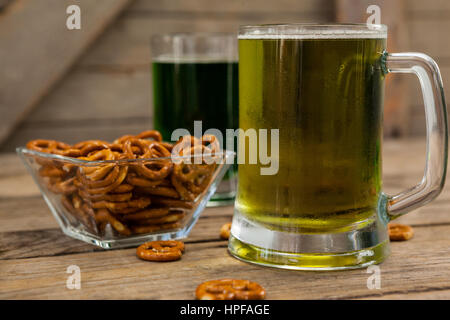 St. Patricks Day zwei Becher Bier mit Brezel auf Holzuntergrund Stockfoto