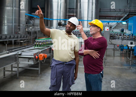 Zwei Arbeiter nach oben zeigend, während diskutieren gemeinsam in der Produktionsanlage Getränke Stockfoto