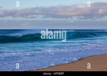 Eine Welle bricht am späten Abend entlang des Strandes auf der Nordküste von Oahu. Stockfoto