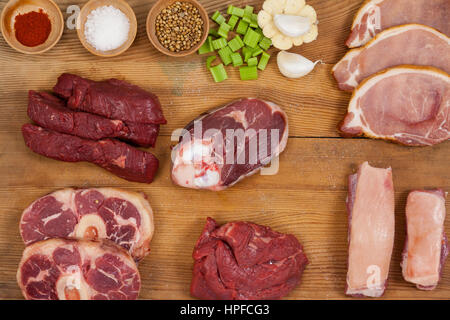 Sorten von Fleisch mit Gewürzen auf Holzbrett vor weißem Hintergrund Stockfoto