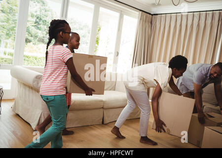 Eltern und Kinder tragen Kartons im Wohnzimmer zu Hause Stockfoto