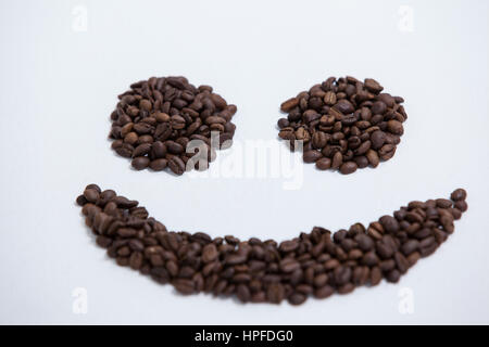 Kaffee-Bohnen bilden Smiley auf weißem Hintergrund Stockfoto