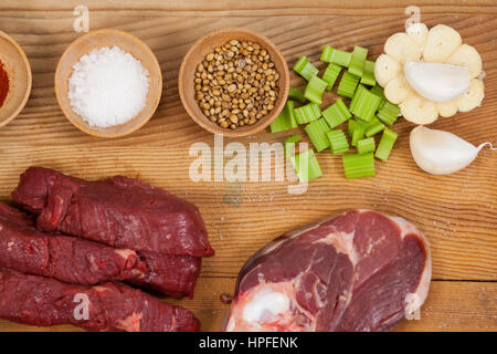 Sorten von Fleisch mit Gewürzen auf Holzbrett vor weißem Hintergrund Stockfoto