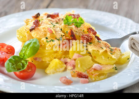 Frisch aus dem Ofen serviert herzhafte Kartoffel-Gratin mit Parmesan-Käse, Sahne und köstlichen Speck aus Südtirol Stockfoto