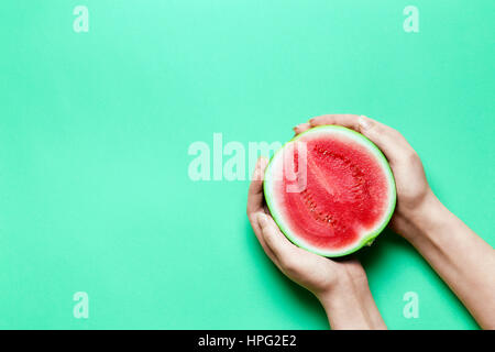 Die Hälfte der Süße Mini-Wassermelone in weiblichen Händen mit grünen Textfreiraum. Stockfoto