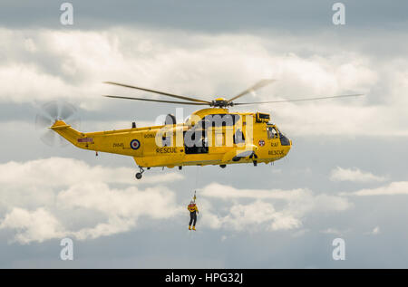 DAWLISH, Großbritannien - 23. August 2014: Royal Navy Sea King Such- und Rettungshubschrauber fliegen auf der Dawlish Airshow Demonstration Winde Rescue Stockfoto