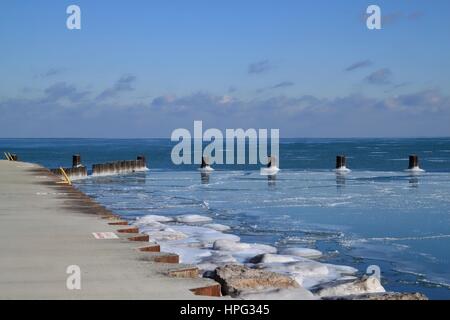 Blick auf Holz- Beiträge auf das Eis eines zugefrorenen und Icy Lake Michigan See in Chicago an einem kalten Januar wider Stockfoto