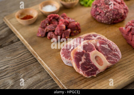 Sorten von Fleisch und Gewürzen auf Holztablett aus Holz Hintergrund Stockfoto