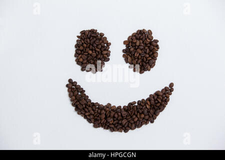 Kaffee-Bohnen bilden Smiley auf weißem Hintergrund Stockfoto