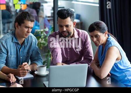 Lächelnde Geschäftsleute Diskussion über Laptop im Büro Stockfoto