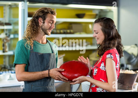 Verkäufer, die Unterstützung der Kunden in Gouda-Käse am Schalter im Lebensmittelgeschäft zu kaufen Stockfoto