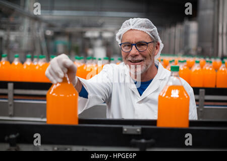Porträt des Lächelns Fabrik Ingenieur Prüfung eine Flasche Saft in Flasche Fabrik Stockfoto