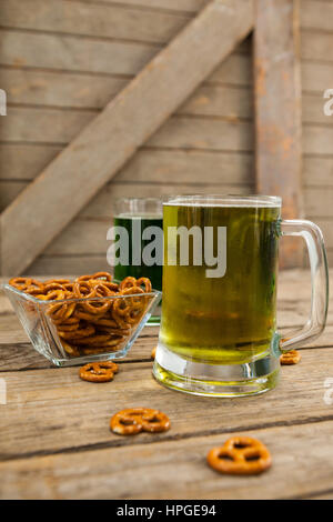 St. Patricks Day zwei Becher Bier mit Brezel auf Holzuntergrund Stockfoto