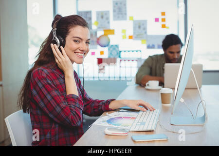 Weibliche Grafiker arbeiten beim hören von Musik im Büro Stockfoto