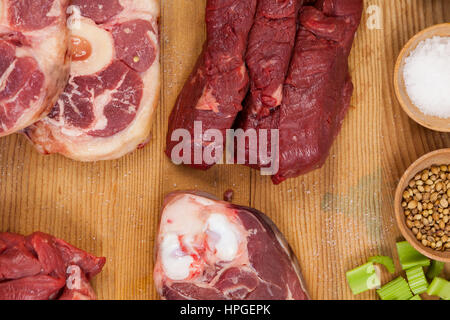 Sorten von Fleisch mit Gewürzen auf Holzbrett vor weißem Hintergrund Stockfoto