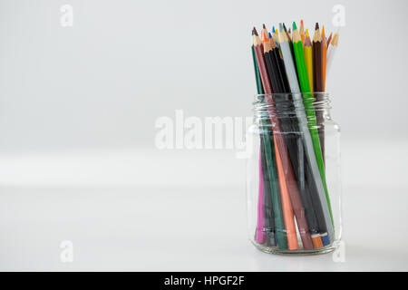 Buntstifte in Glas auf weißem Hintergrund gehalten Stockfoto