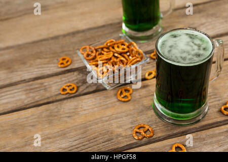 St. Patricks Day 2 Tassen grüne Bier mit Brezel auf Holzuntergrund Stockfoto