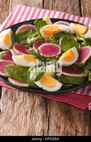 Gesunder Salat mit Radieschen, Eiern, Spinat und Salat mischen close-up auf dem Tisch. vertikale Stockfoto