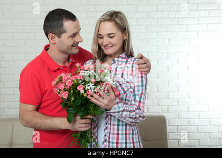 Valentinstag, Jubiläum, Event-Konzept - junge Frau erhält ein Geschenk von Blumenstrauß von ihrem Freund Stockfoto