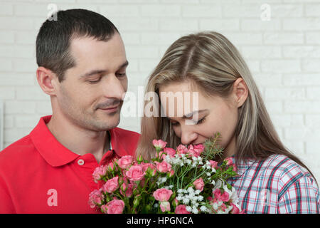 Valentinstag, Jubiläum, Event-Konzept - junge Frau erhält ein Geschenk von Blumenstrauß von ihrem Freund Stockfoto