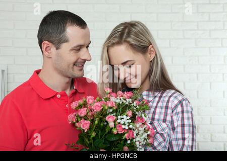 Valentinstag, Jubiläum, Event-Konzept - junge Frau erhält ein Geschenk von Blumenstrauß von ihrem Freund Stockfoto