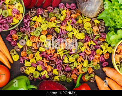 Bunte Nudeln auf einem Tisch mit frischem Gemüse (Rüben, Grüns, Karotten, Tomaten, Paprika). Gesunde Ernährung-Konzept. Die Ansicht von oben Stockfoto