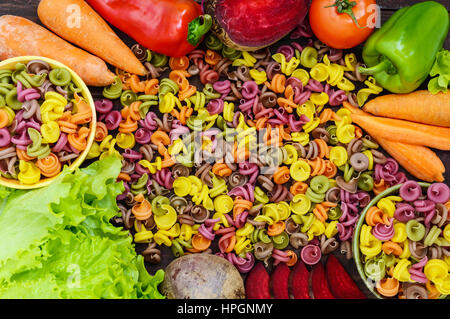 Bunte Nudeln auf einem Tisch mit frischem Gemüse (Rüben, Grüns, Karotten, Tomaten, Paprika). Gesunde Ernährung-Konzept. Die Ansicht von oben Stockfoto