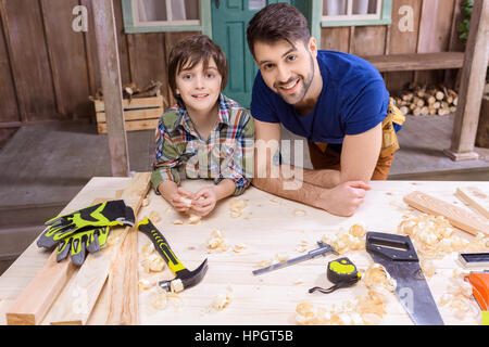 Vater und Sohn gestützt auf Tabelle mit Werkzeugen und lächelt in die Kamera Stockfoto