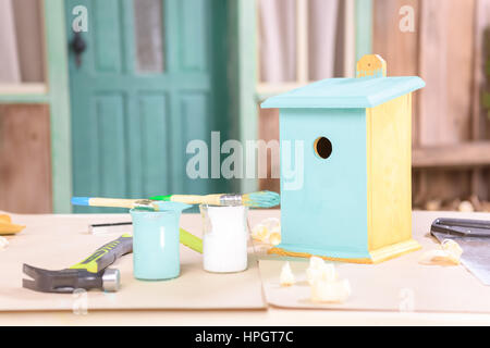 handgemachte kleine Vogelhaus mit Farben und Werkzeuge auf Tisch Stockfoto