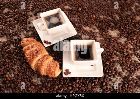 Kaffeebohnen und leckere Croissant Ansicht von oben Stockfoto