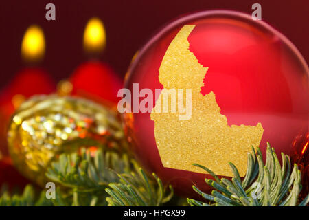 Eine glänzende rote Christbaumkugel mit der goldenen Form von Idaho. (Serie) Stockfoto