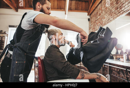 Friseur Salon Kap zu Client setzen. Männliche Friseur bei der Arbeit mit schöner Mann auf Stuhl sitzend. Stockfoto