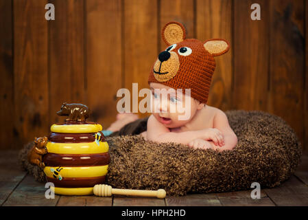 Neugeborenes Baby in einer Strickmütze trägt. Umgeben von den Teddybären auf dem hölzernen Hintergrund. Stockfoto