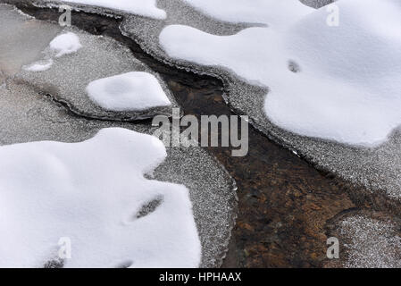 Gefrorene Flüsschen mit frischem Schnee auf den Felsen im winter Stockfoto