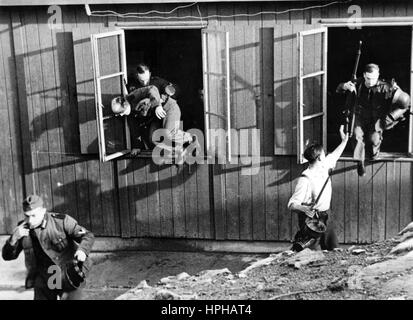 Das Bild der Nazi-Propaganda zeigt deutsche Wehrmachtssoldaten einer Artillerieeinheit an einem Stützpunkt der Westfront, die an einer Übung teilnehmen und auf dem Weg sind, ihre Waffen abzuholen. Veröffentlicht im November 1942. Ein Nazi-Reporter hat auf der Rückseite des Bildes auf 30.11.1942 geschrieben: "Alarm bei einer Küstenbatterie. 30 Sekunden nach dem Alarm springen die Schützen aus den Fenstern und Türen der Baracken und beeilen sich zu ihren Gewehrpunkten." Fotoarchiv für Zeitgeschichte - KEIN KABELDIENST - | weltweite Nutzung Stockfoto