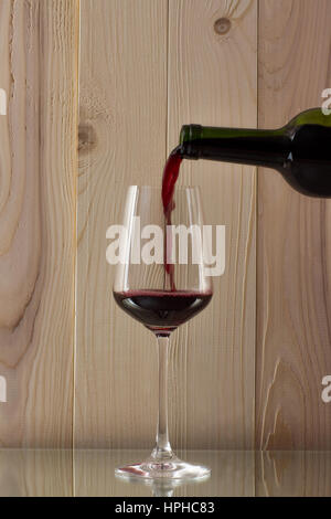 gegossen in eine Flasche Rotwein mit ein brillantes Glas Oon Stand ein Glas Rotwein Stockfoto