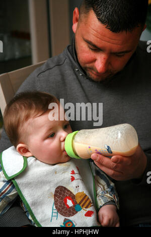 Vater mit der Flasche füttern sein Sohn Stockfoto