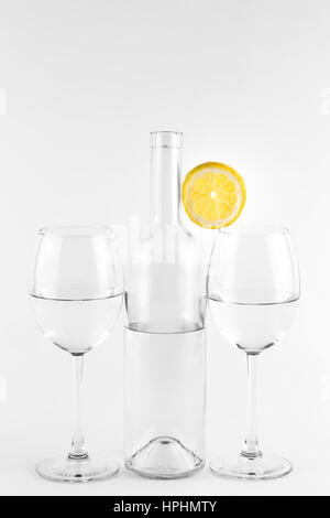Isolierte durchsichtige Flasche und Gläser mit Zitrone auf weißem Hintergrund Stockfoto