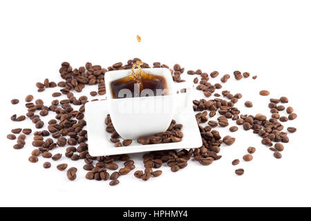 Tasse mit leckeren Kaffeebohnen und Spritzwasser isoliert auf weiss Stockfoto