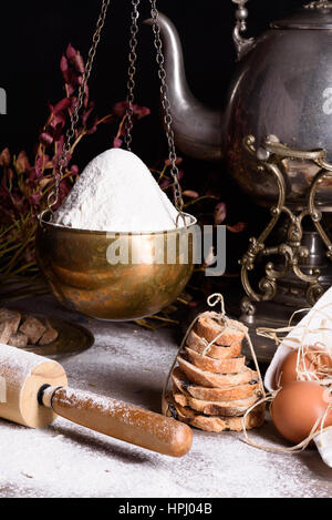 Backzutaten - Mehl, Eiern, Backpulver Brot. Mehlbasis Essen Stilleben mit antiken Teekanne gebacken. Stockfoto