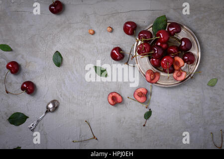 Kirsche auf einem Teller über graue rustikale Hintergrund, Textfreiraum, Draufsicht. Frische Beeren, Obst. Stockfoto