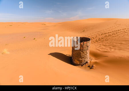 Blick über die Dünen des Erg Chebbi Wüste bei Merzouga in Marokko mit einem trockenen Wasser gut im Vordergrund. Stockfoto